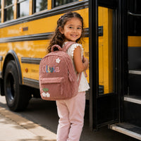 Girl boarding school bus with personalized name backpack