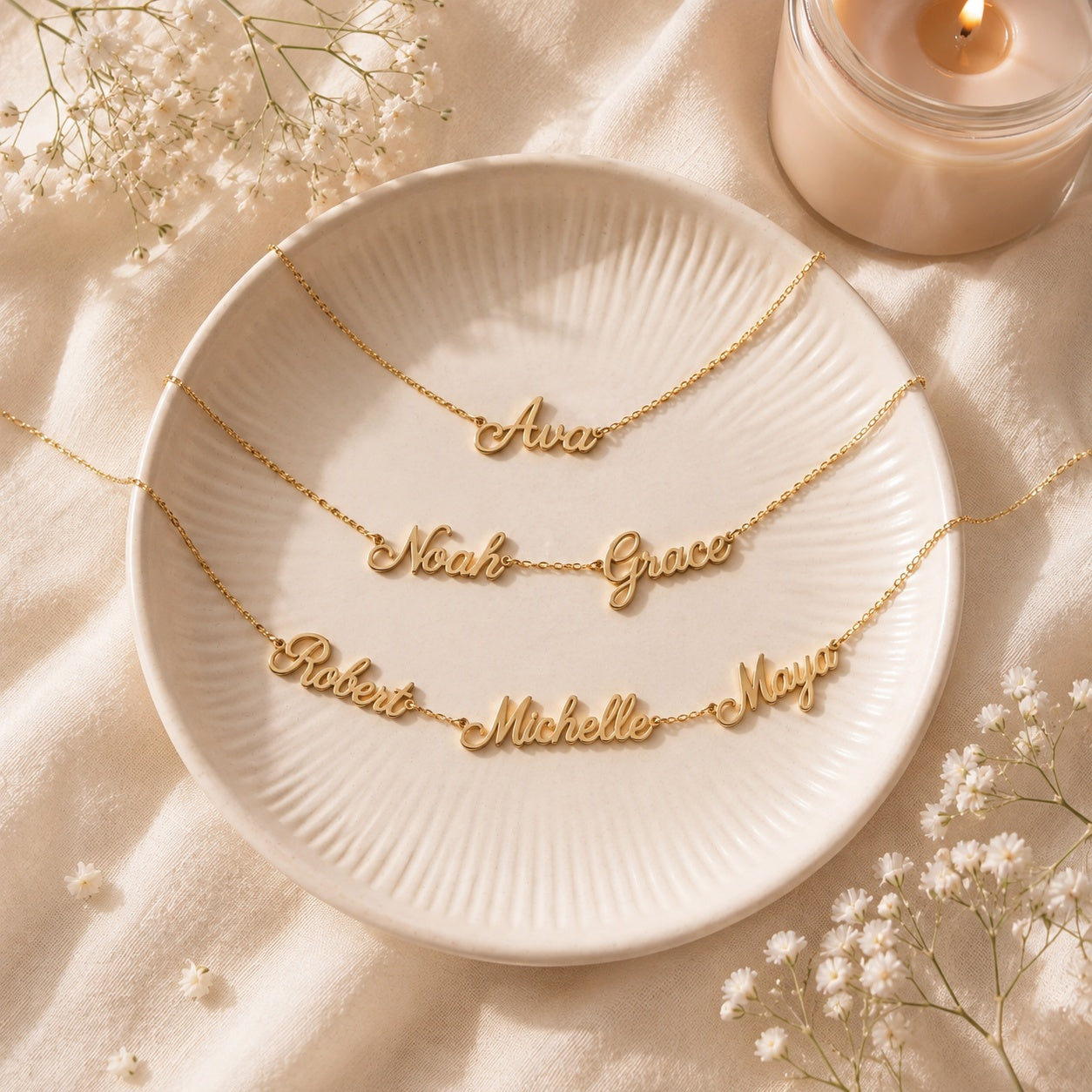 Three gold personalized name necklaces on a cream dish showing the one, two and three name options: Ava, then Noah and Grace, then Robert, Michelle and Maya
