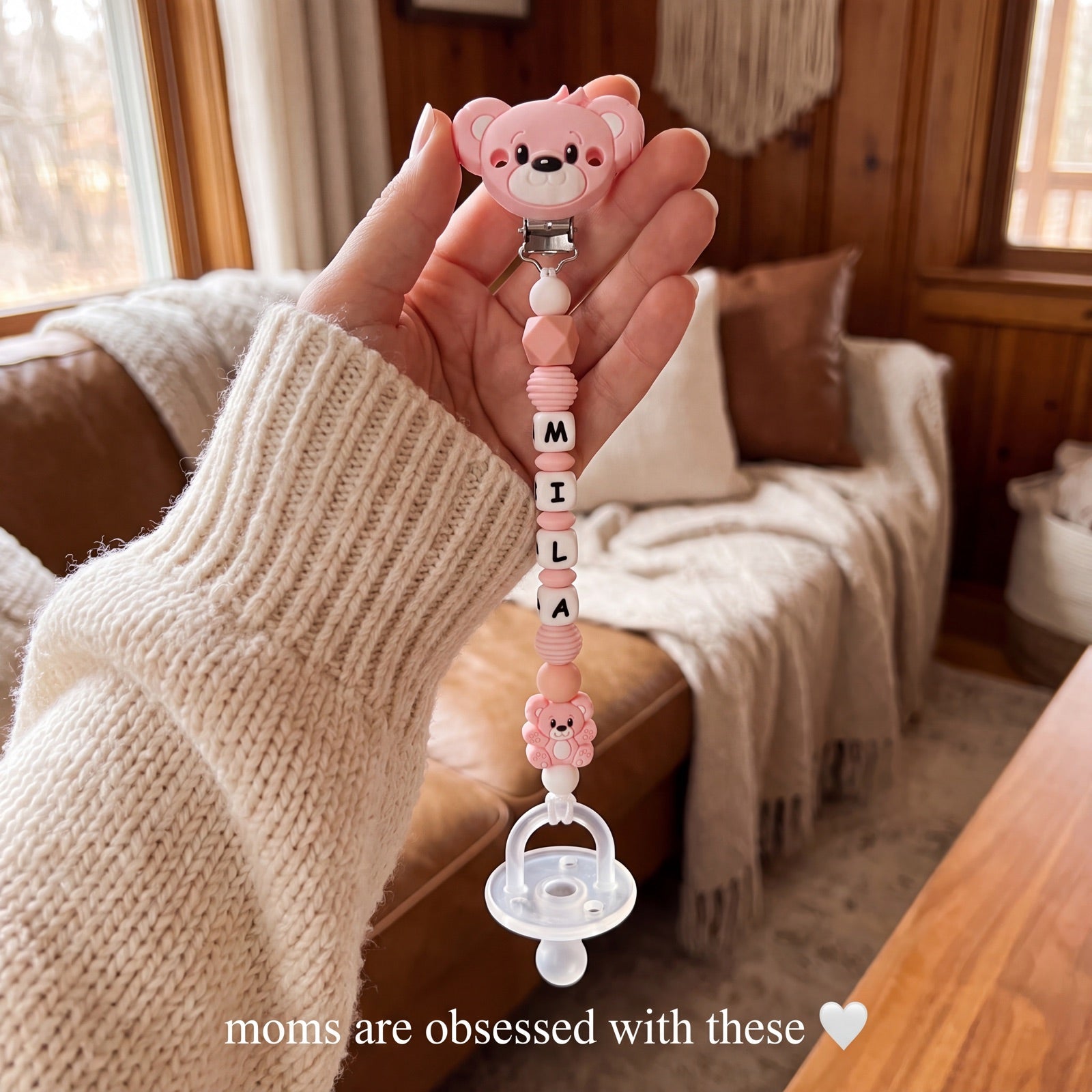 Mom holding a personalized pink pacifier clip hand-beaded with the name Mila