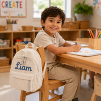 Boy in classroom with cream personalized name backpack