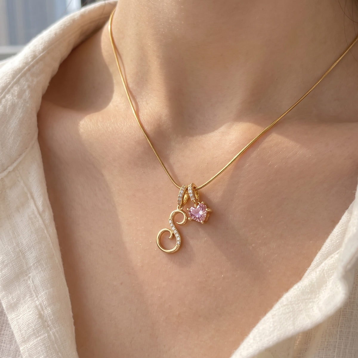 A young woman wearing the gold initial S necklace, close-up on the collarbone