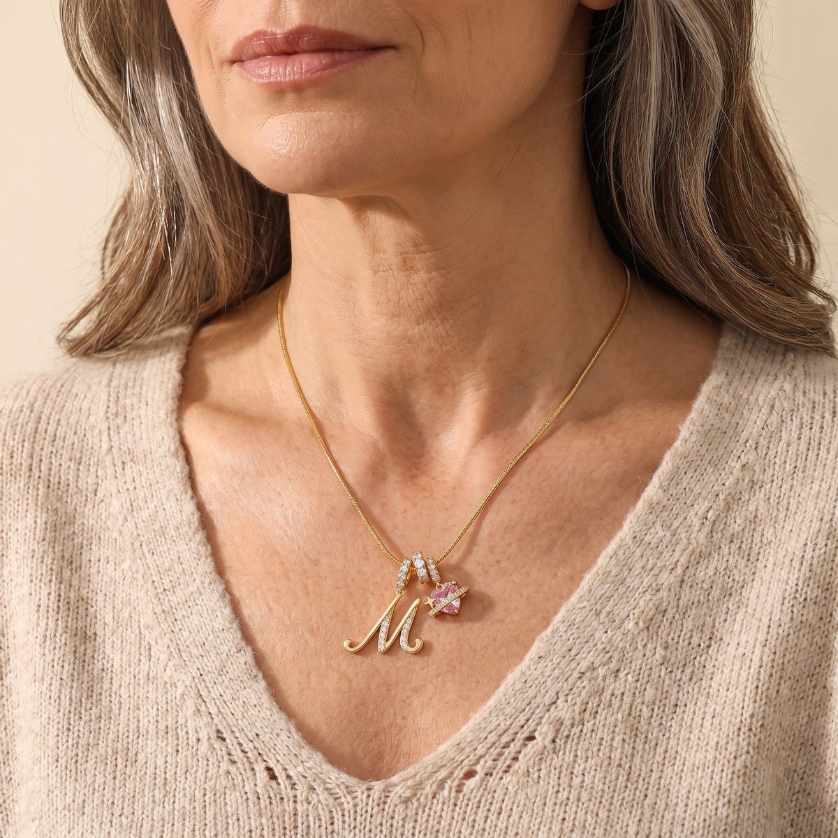 A mature woman in her 50s wearing the gold initial M necklace