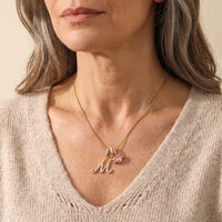 A mature woman in her 50s wearing the gold initial M necklace