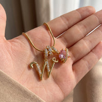 Close-up detail of the gold initial W necklace in an open palm