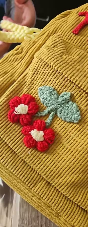 Yellow backpack with a knitted cherry charm