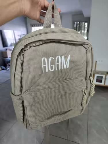 Khaki backpack with Agam in white print lettering