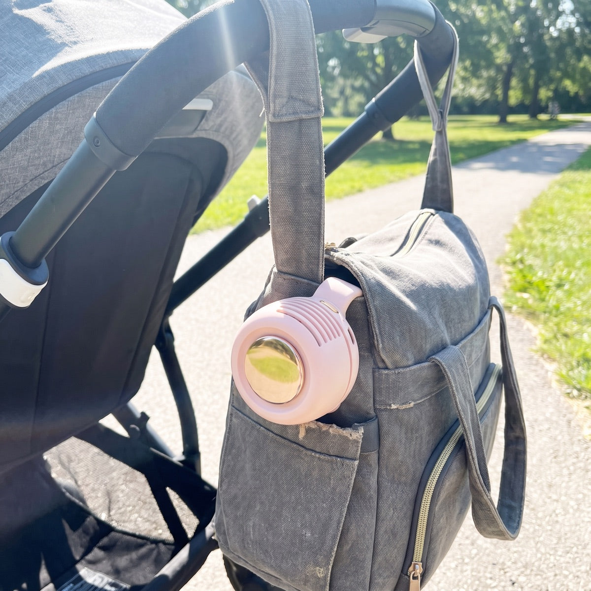 Customer photo — Soft Pink ChillClip on a stroller bag strap outdoors